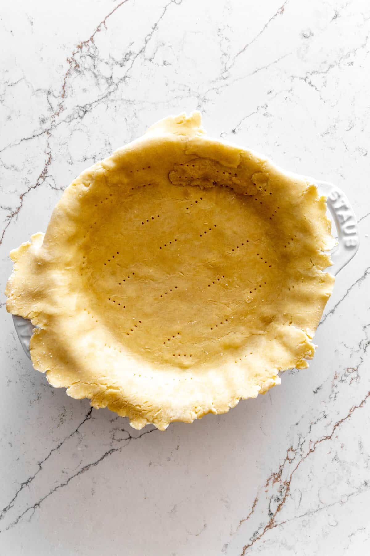 Unbaked pie crust in a white pie pan.