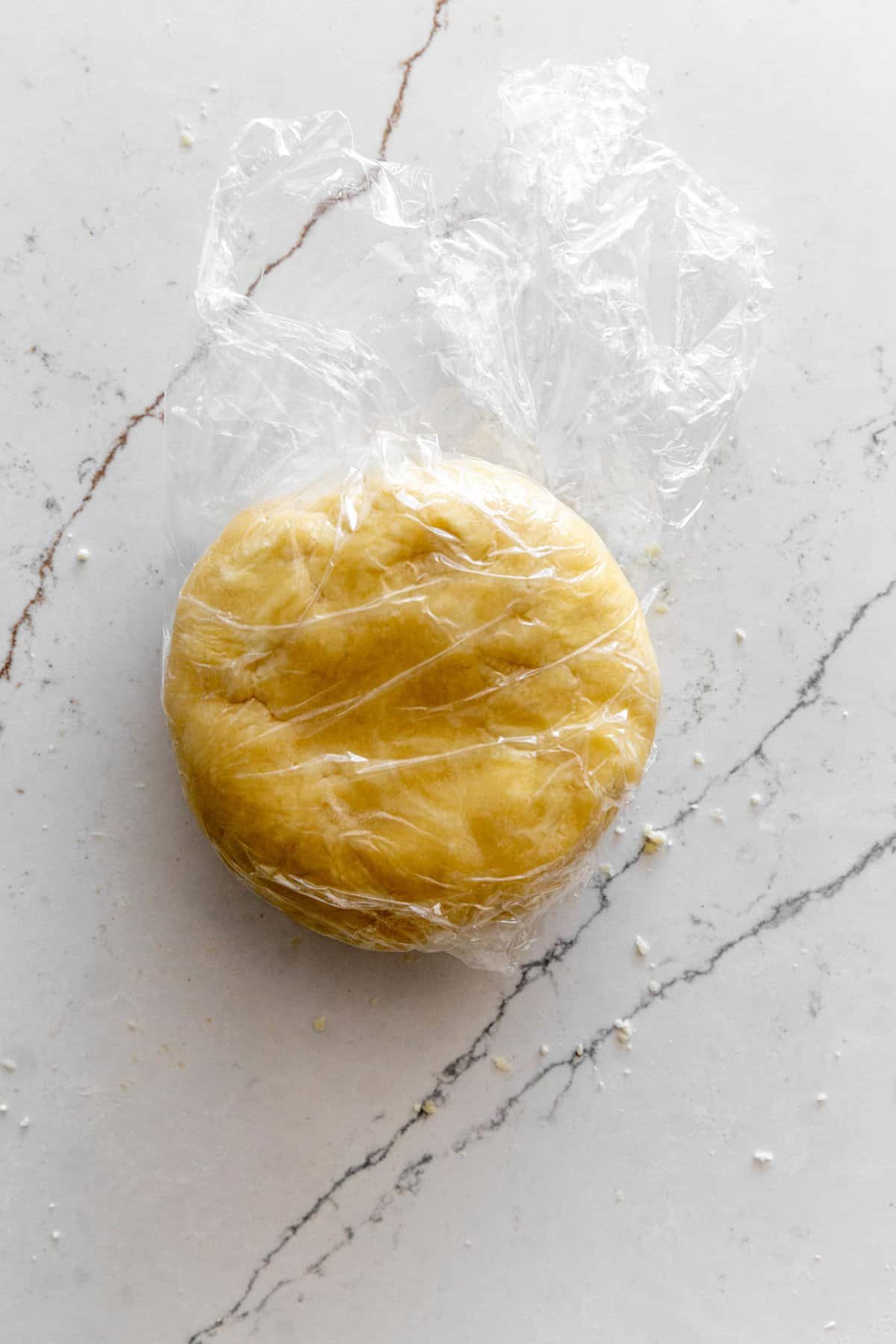 Disk of pie crust dough wrapped in plastic wrap.