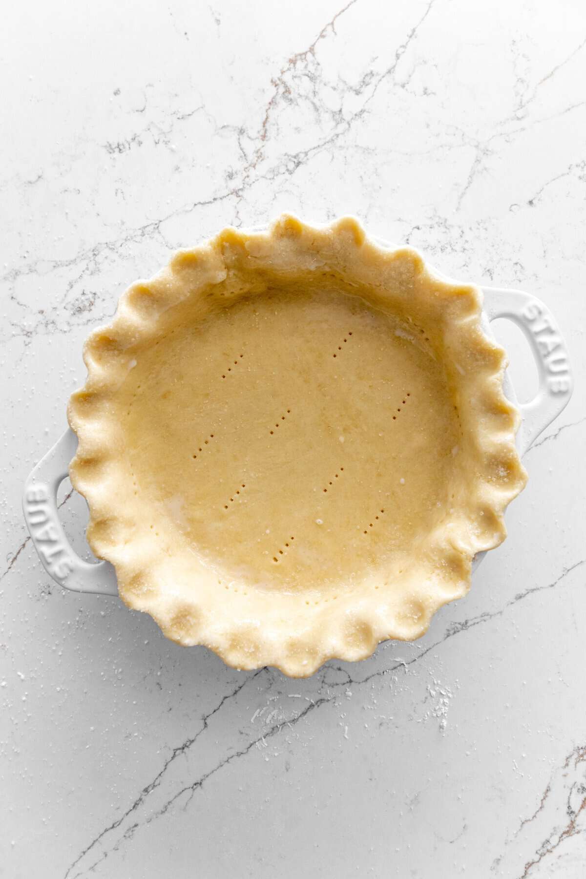 Unbaked pie crust in a white pie dish.