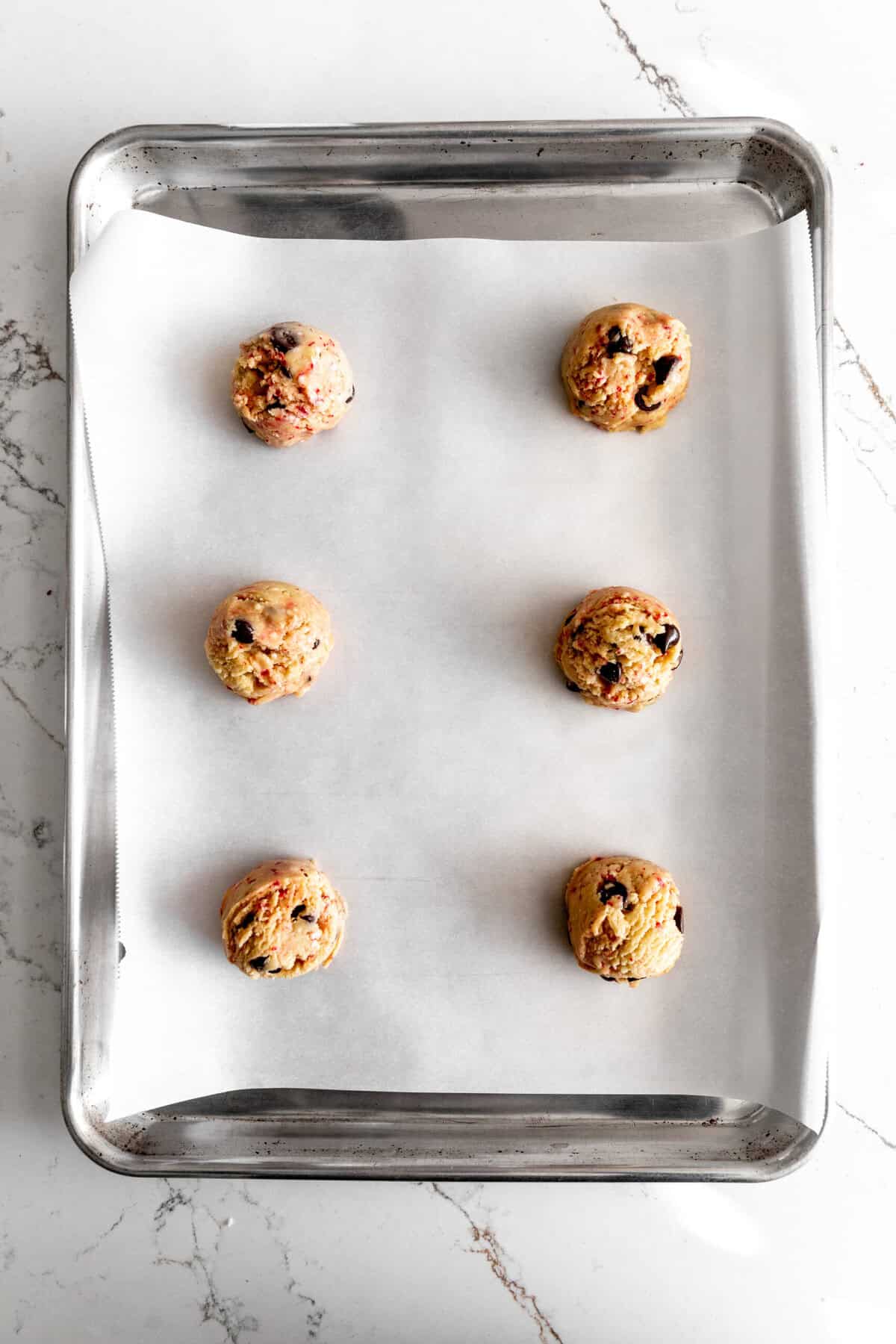 Unbaked candy cane chocolate chip cookies on a baking sheet.