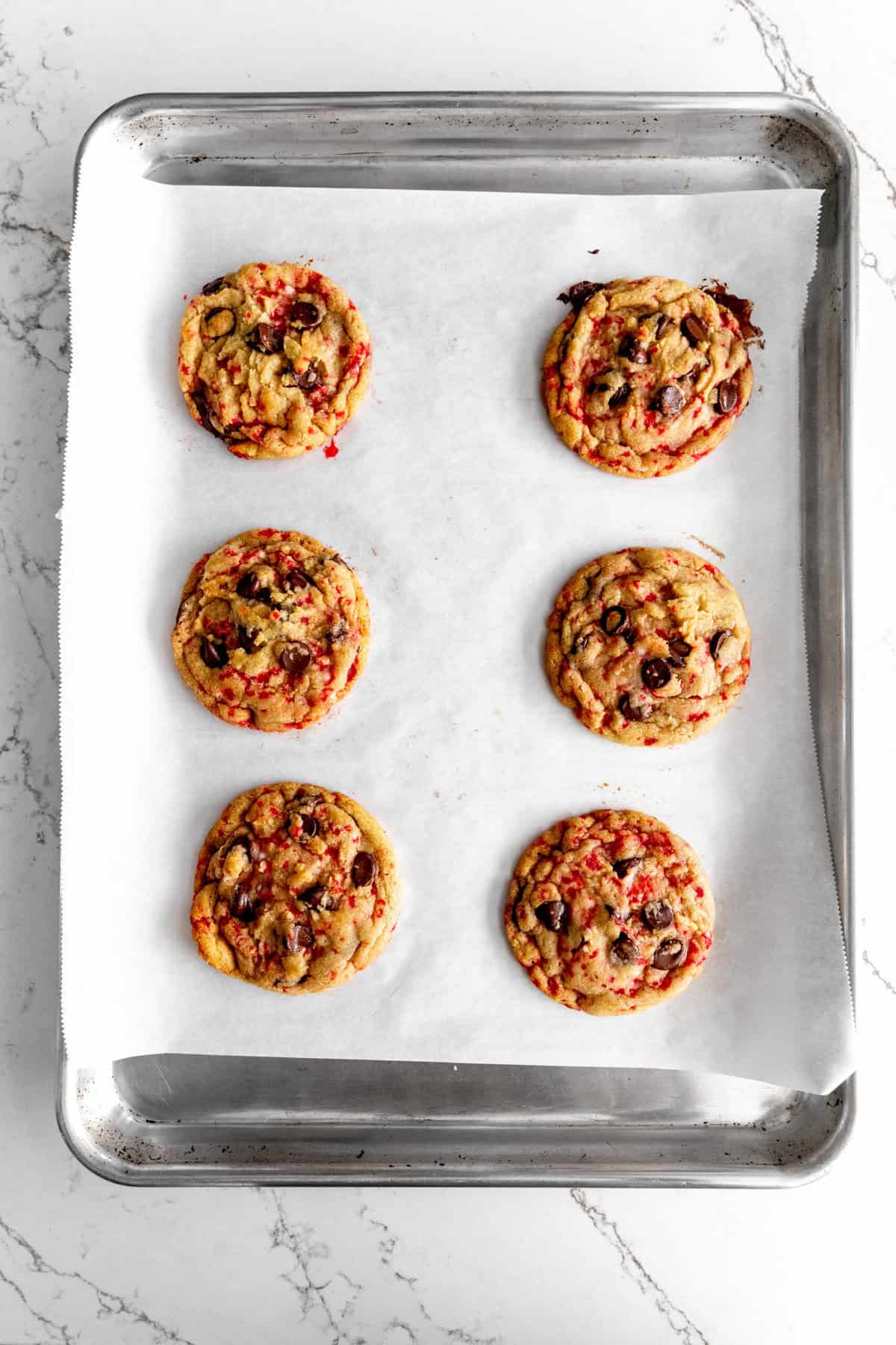 Baked candy cane chocolate chip cookies on a baking sheet.