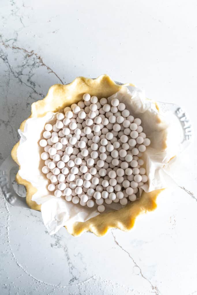 Unbaked pie crust filled with ceramic pie weights.