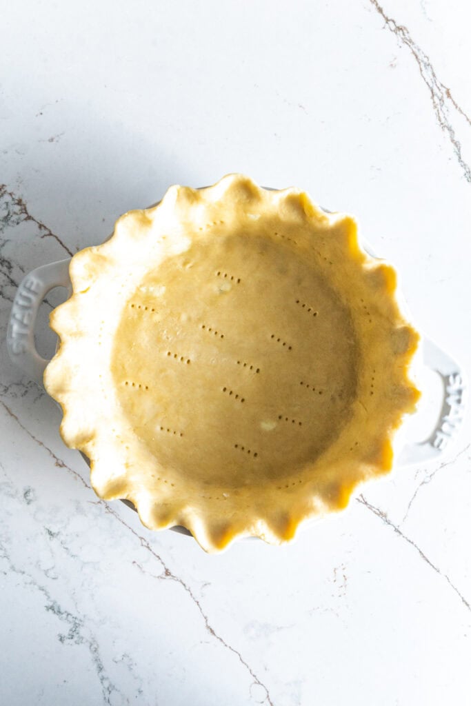 Unbaked pie crust in a white dish.