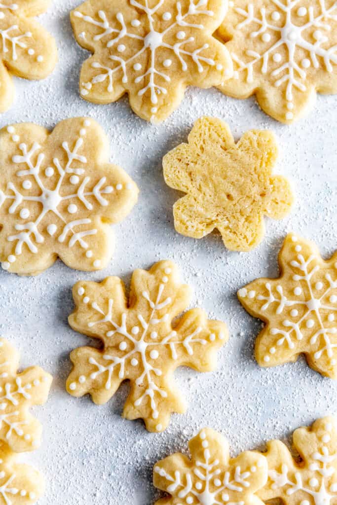 Flipped over snowflake sugar cookie surrounded by more cookies.