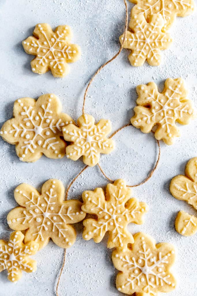 Snowflake sugar cookies on a light blue background with brown twine.