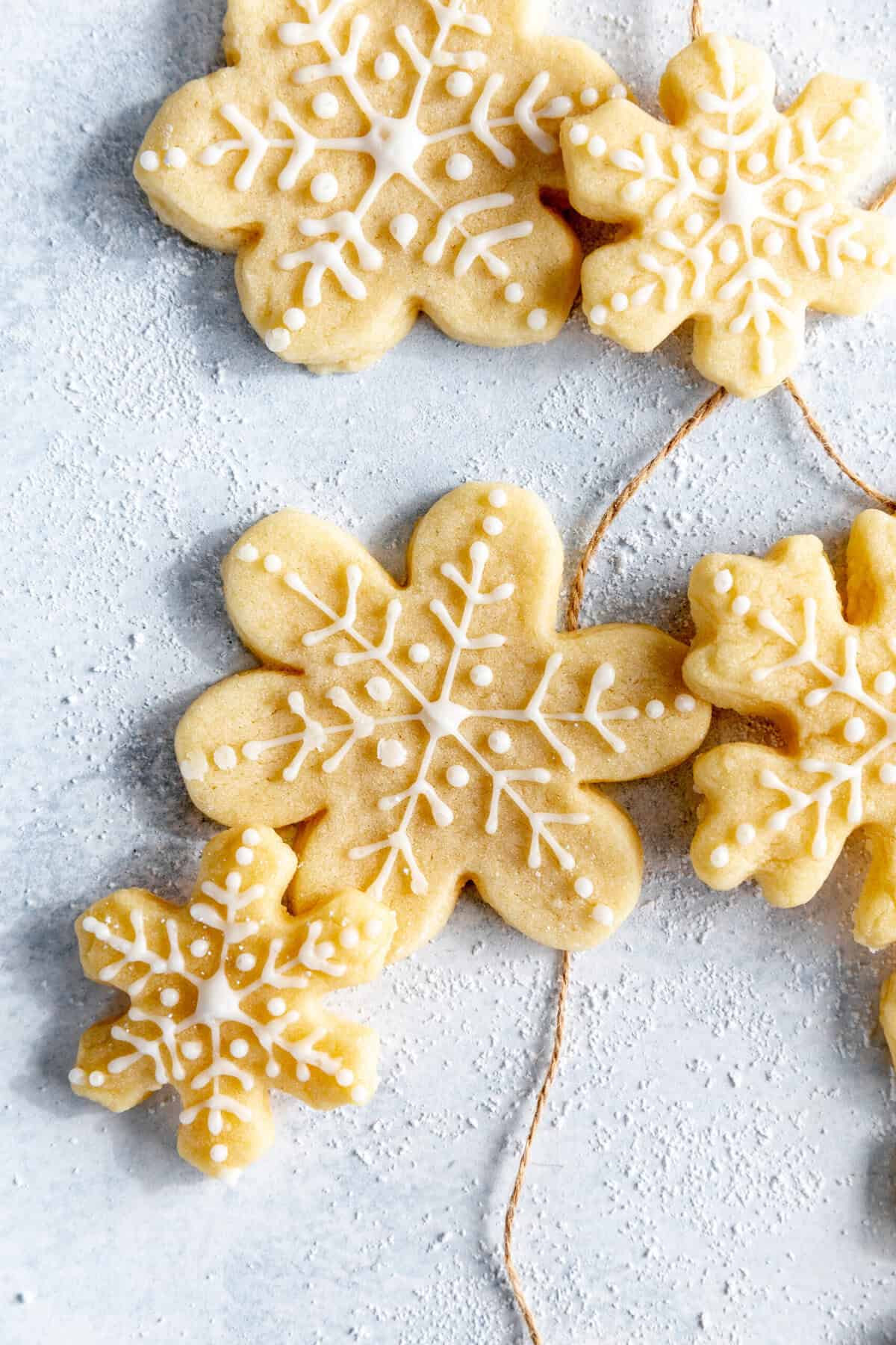 Snowflake sugar cookies on a light blue background with brown twine.