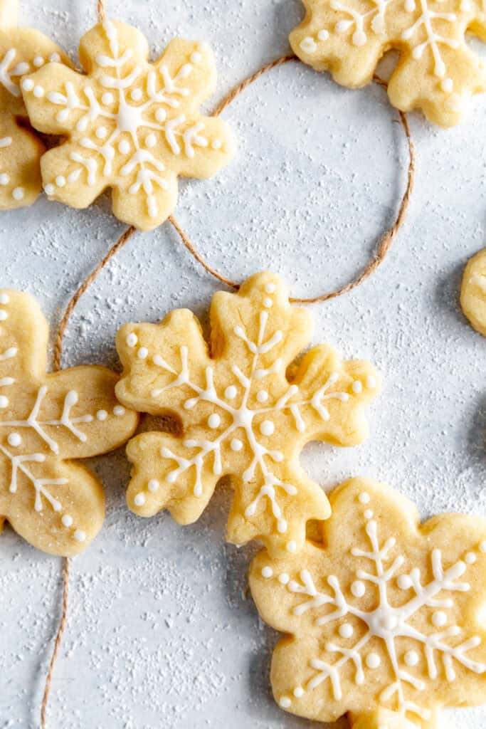 Snowflake sugar cookies on a light blue background with brown twine.