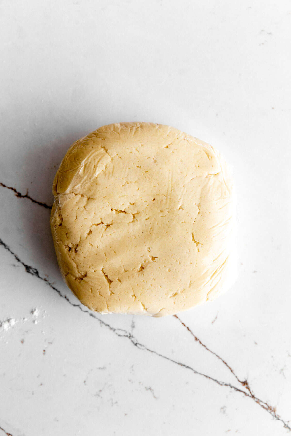 Disk of sugar cookie dough wrapped in plastic wrap.