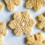 Snowflake frosted sugar cookies on a light blue surface.