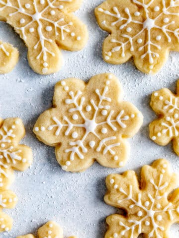 Snowflake frosted sugar cookies on a light blue surface.