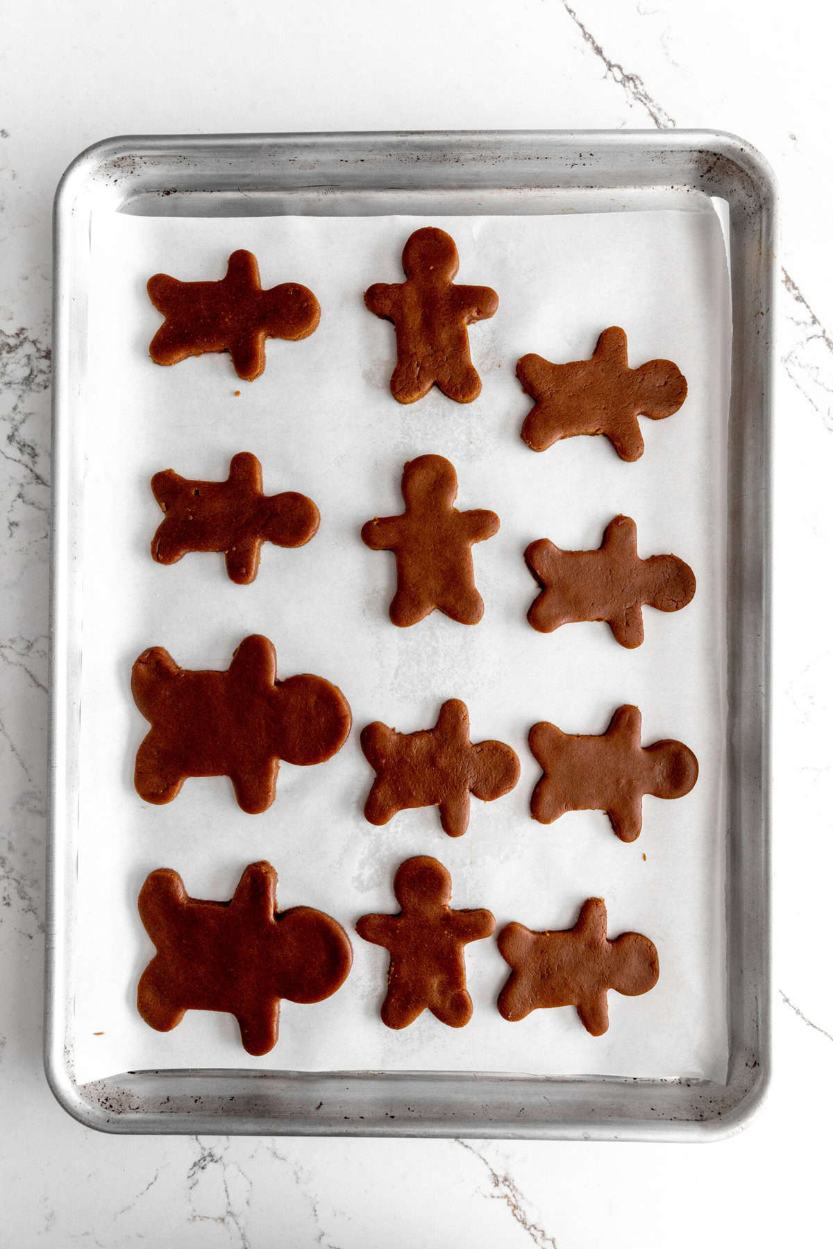 Unbaked gingerbread men on a baking sheet.