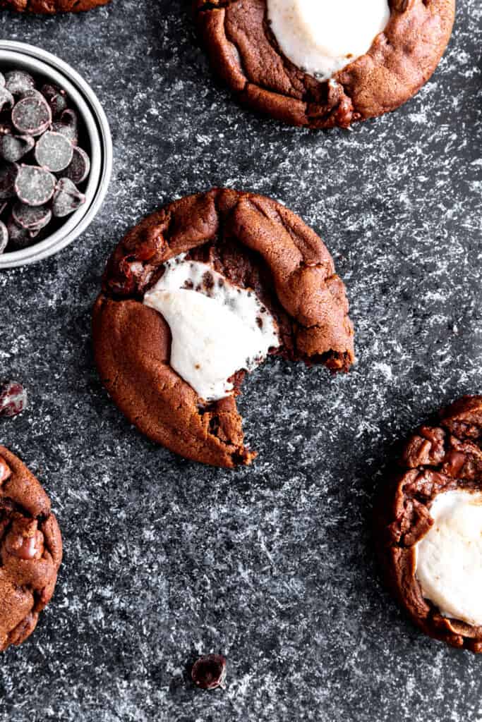 Hot chocolate cookie with a bite taken out of it and a cup of chocolate chips.