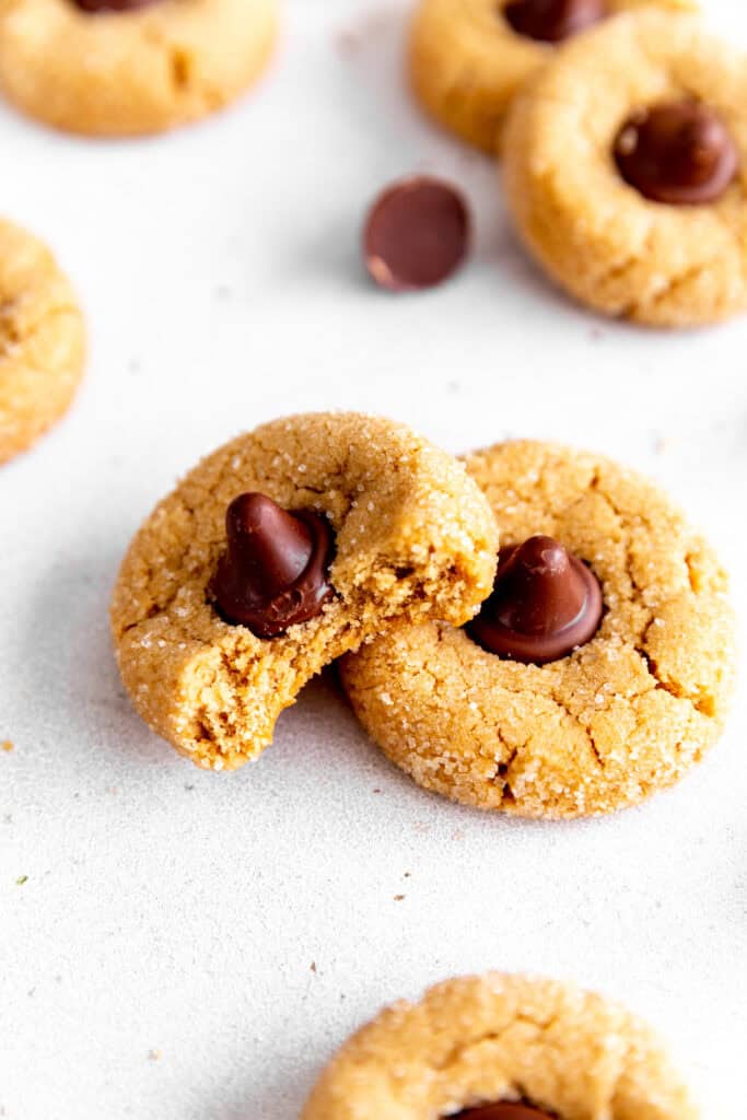 Peanut butter blossom with a bite taken out of it stacked on another cookie.