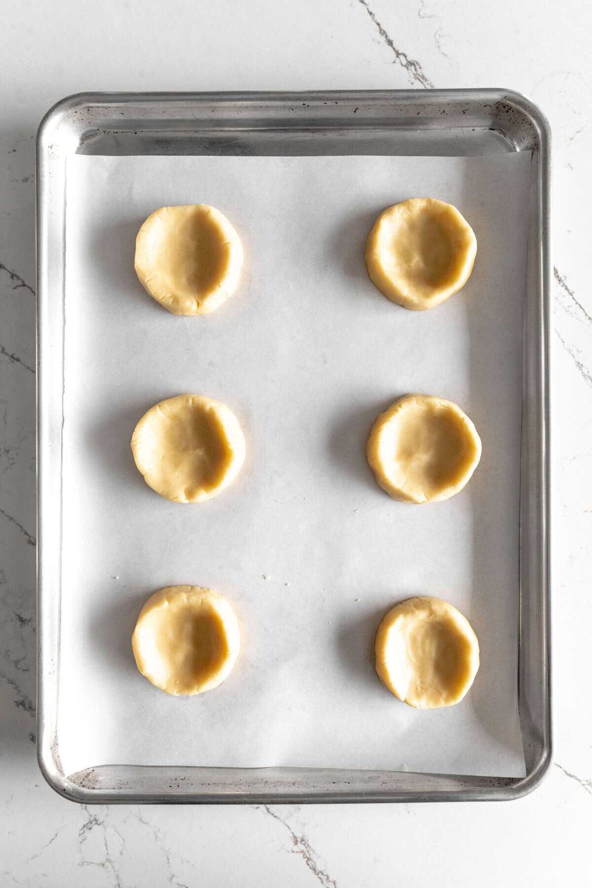 Unbaked pecan pie cookies on a baking sheet.