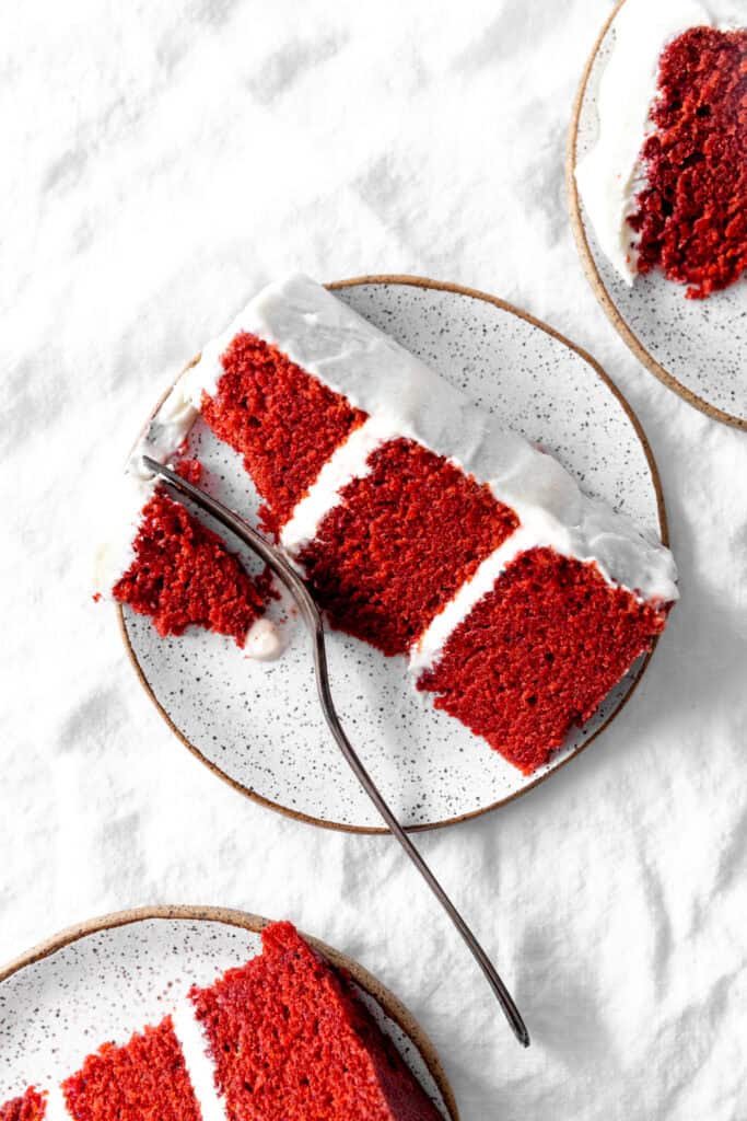 Fork cutting into a slice of red velvet cake.