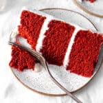 Fork cutting into a slice of red velvet cake.