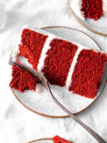 Fork cutting into a slice of red velvet cake.