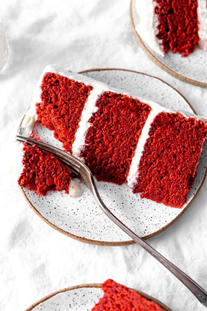 Fork cutting into a slice of red velvet cake.