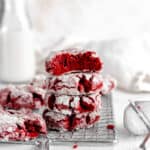 Red velvet crinkle cookie with a bite taken out of it on top of a stack of cookies.