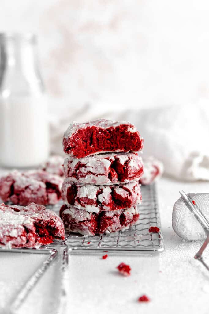 Red velvet crinkle cookie with a bite taken out of it on top of a stack of cookies.