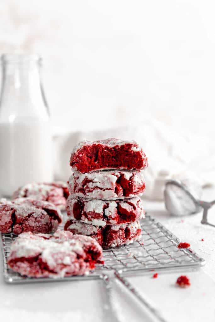 Red velvet crinkle cookie with a bite taken out of it on top of a stack of cookies.