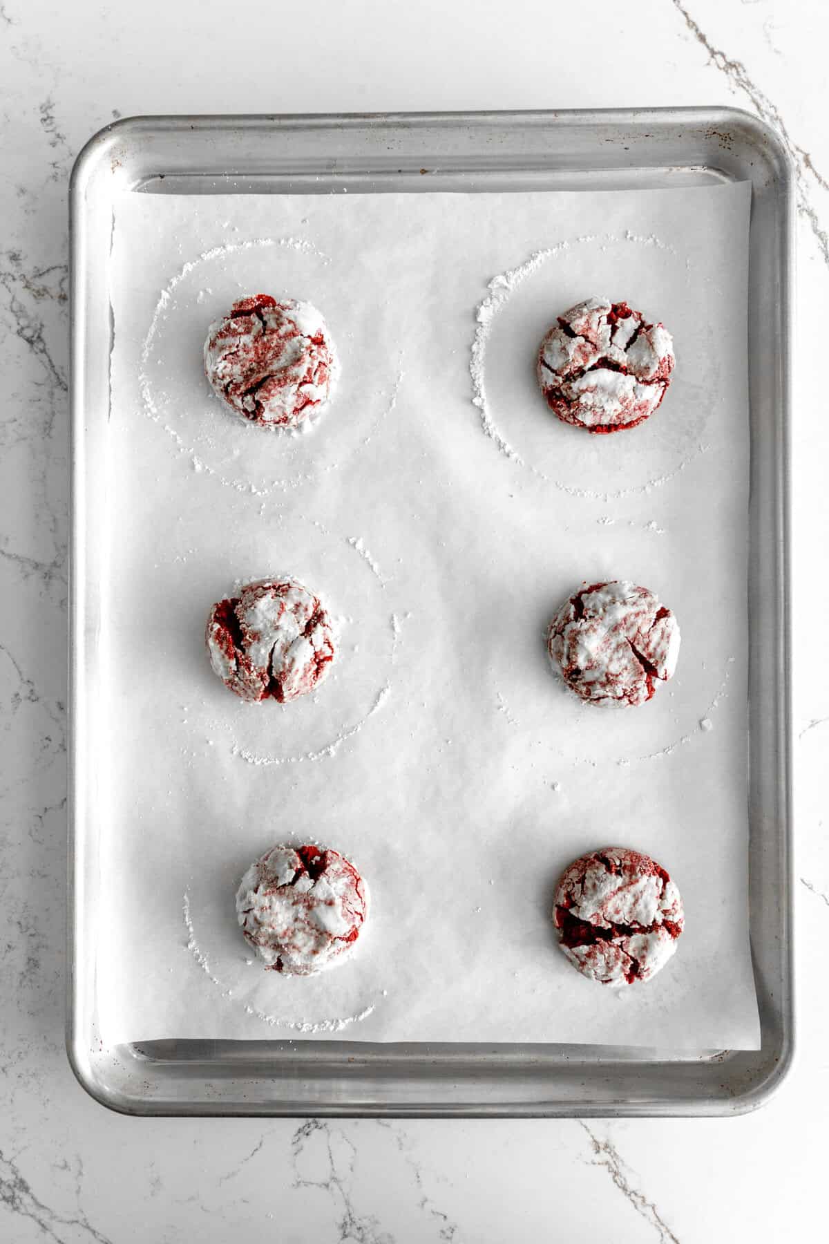 Baked red velvet crinkle cookies on a baking sheet.