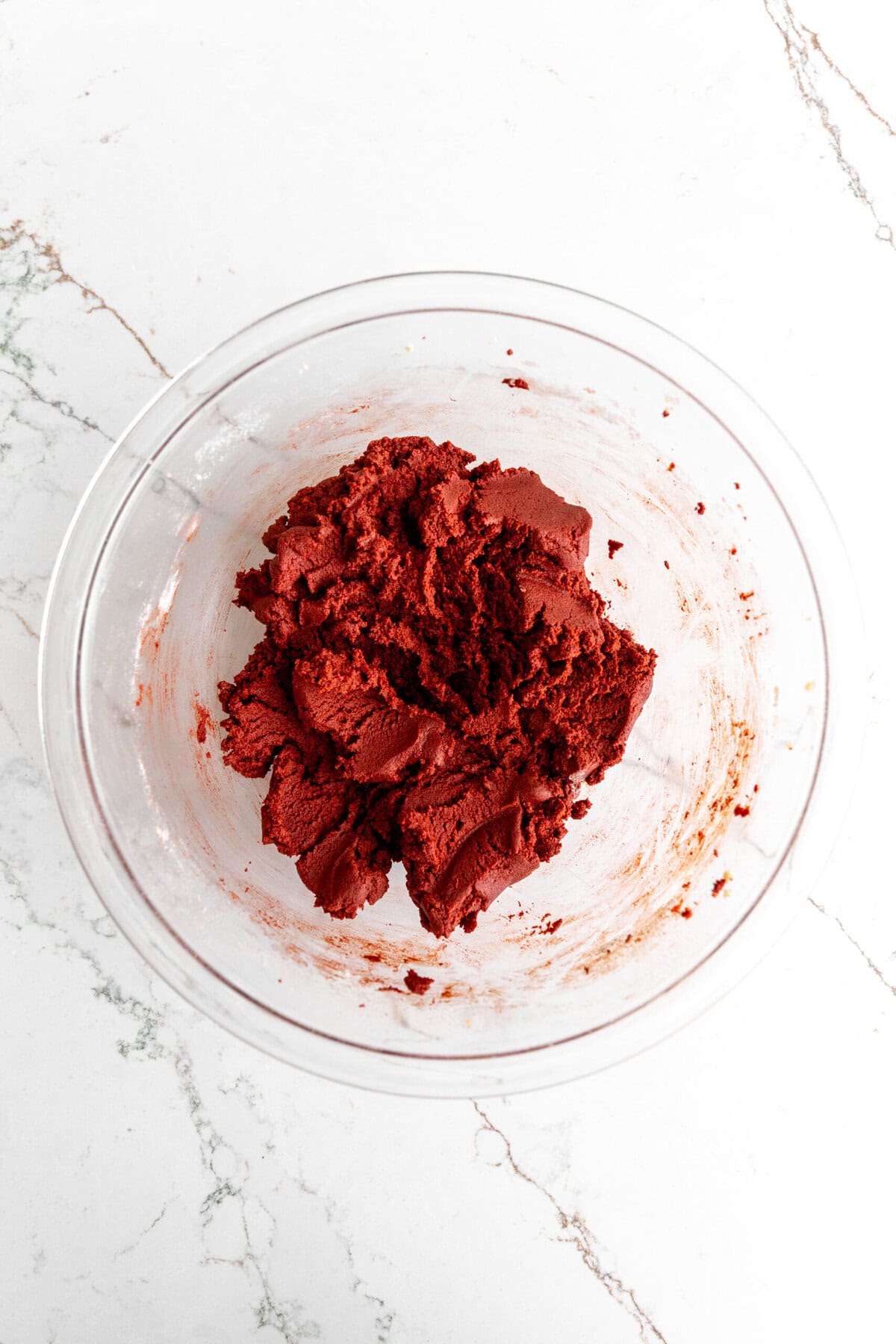 Glass bowl of red velvet crinkle cookie dough.