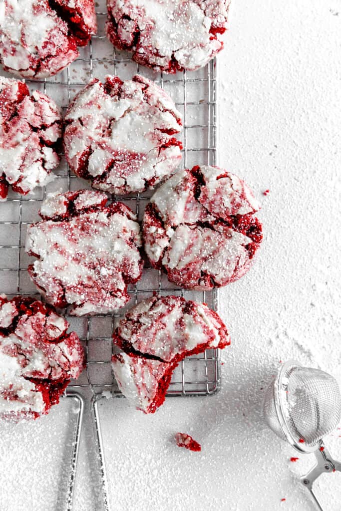 Red velvet crinkle cookie with a bite taken out of it on a wire cooling rack.