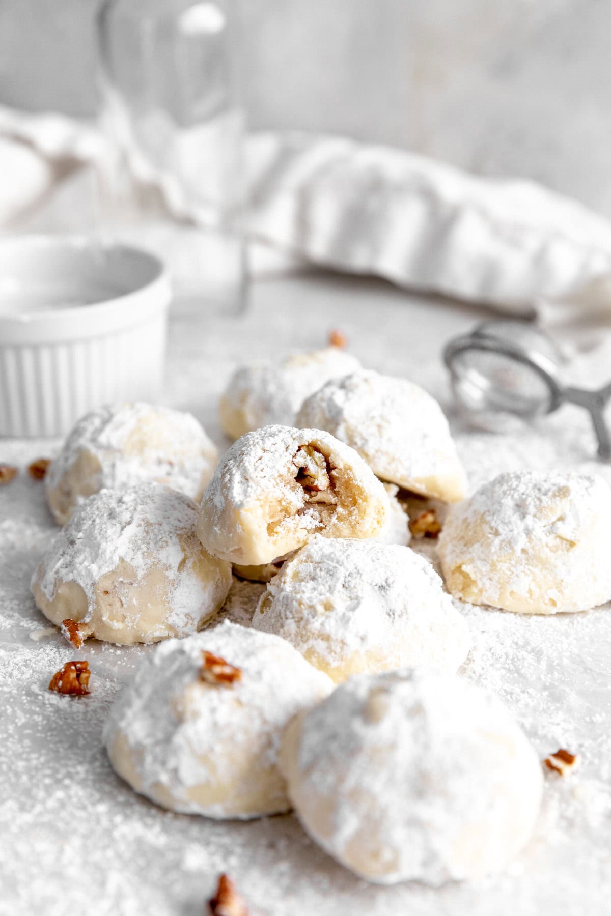 Snowball cookie with a bite taken out of it in a pile of more cookies.