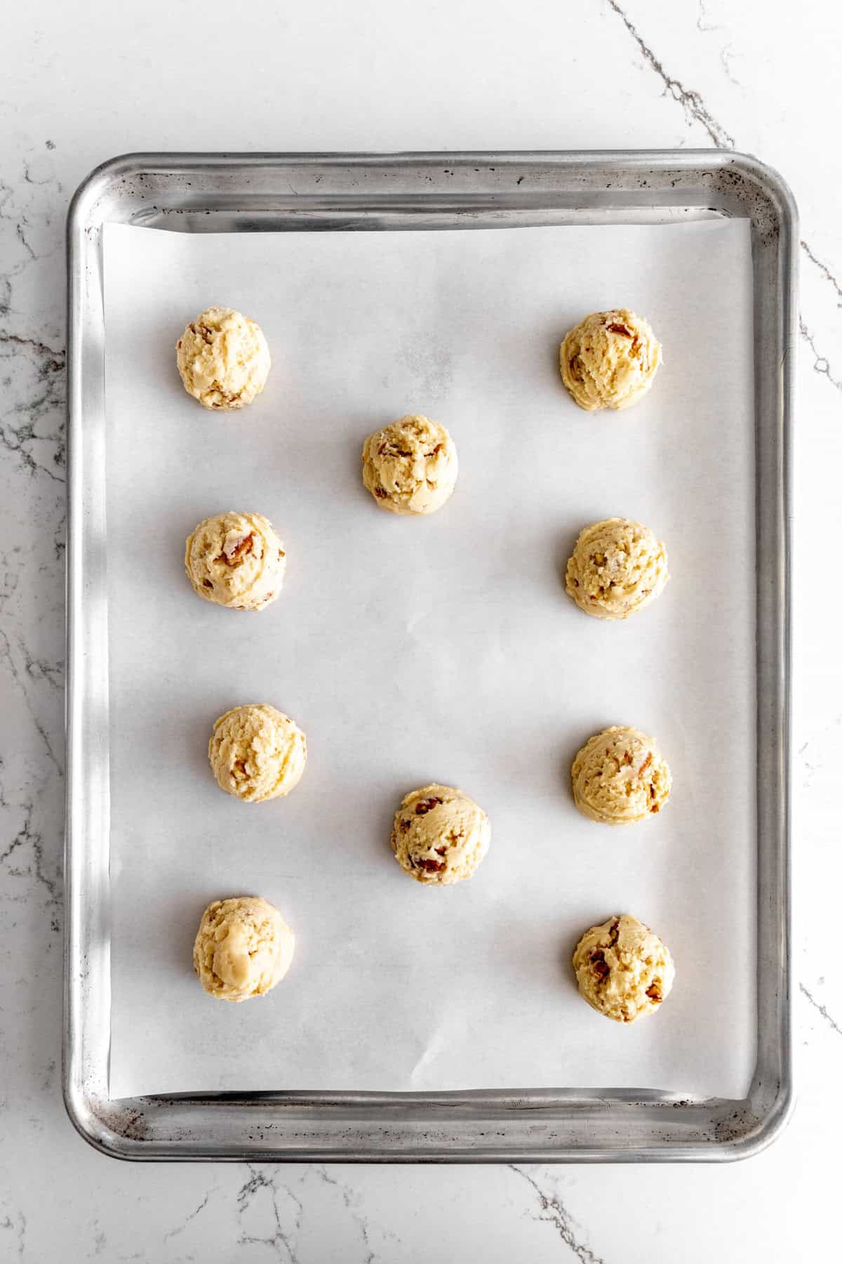 Unbaked snowball cookies on a baking sheet.