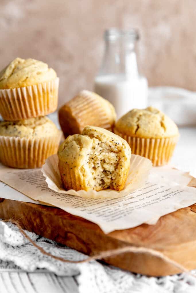 Almond poppy seed muffin with a bite taken out of it in front of a jug of milk.