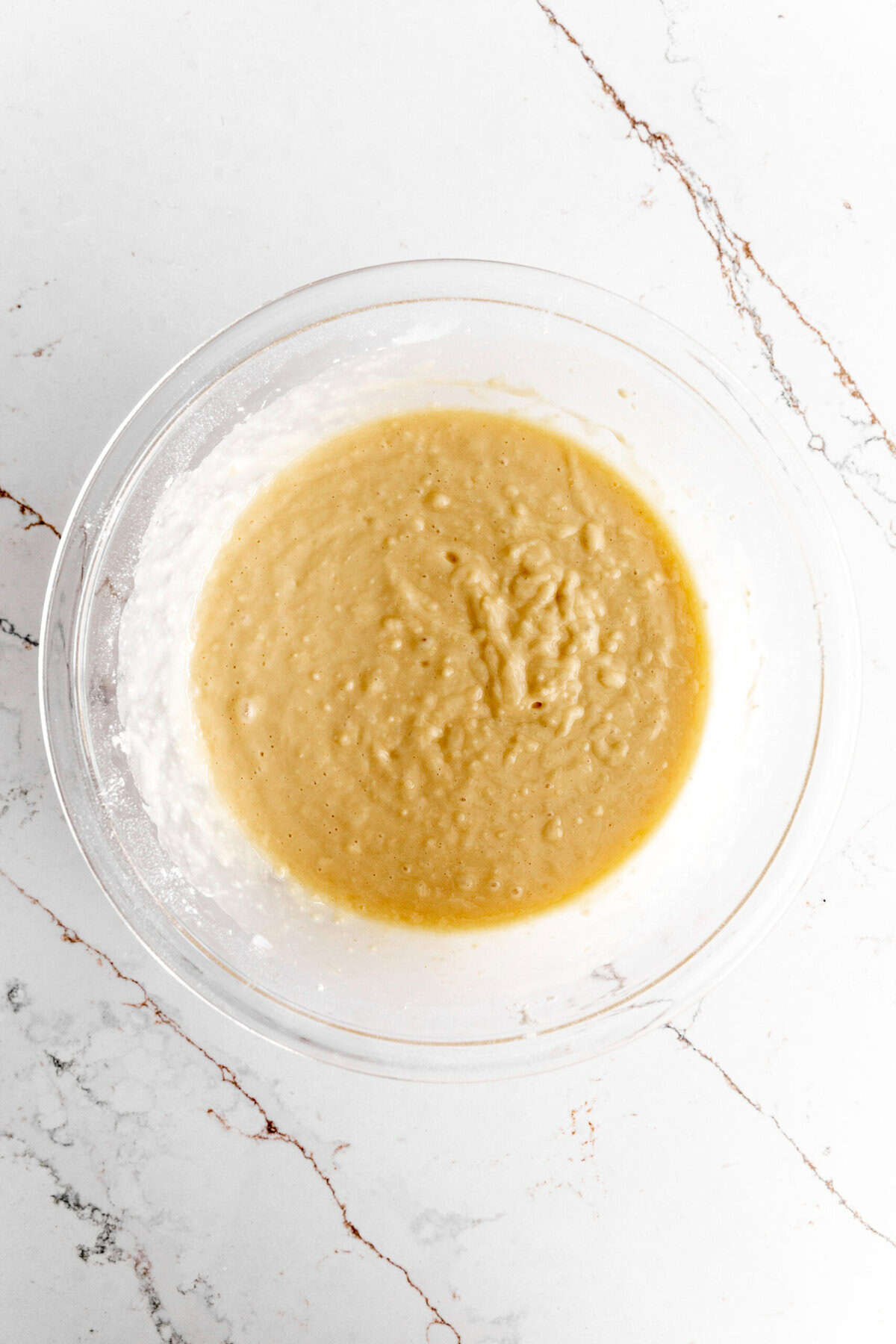 Glass bowl filled with the wet ingredients for muffin batter.