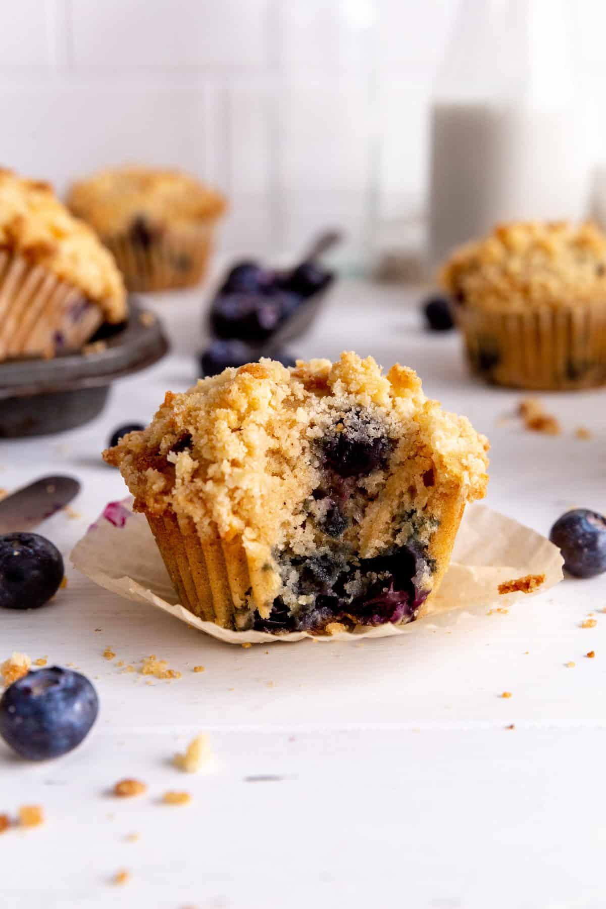 Blueberry muffin with a bite taken out of it and a jug of milk.