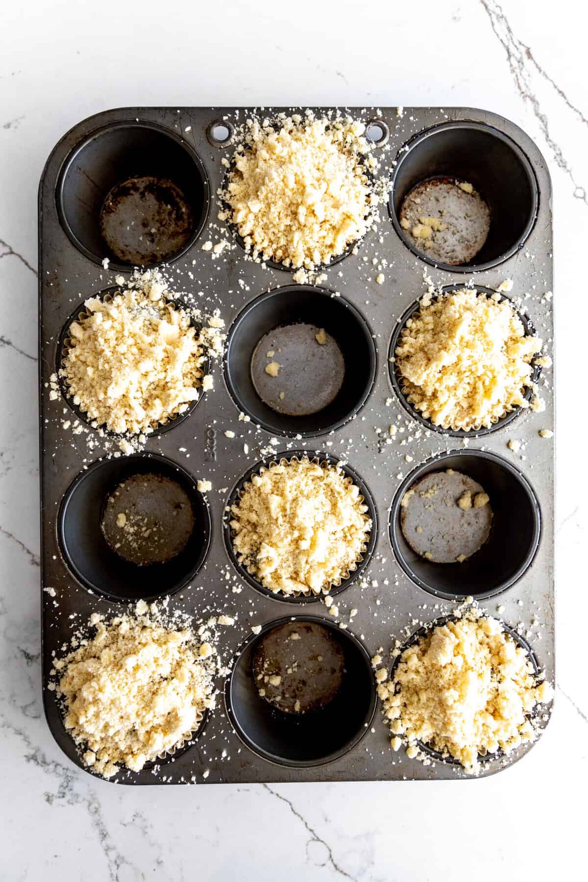 Unbaked blueberry muffins in a baking pan.