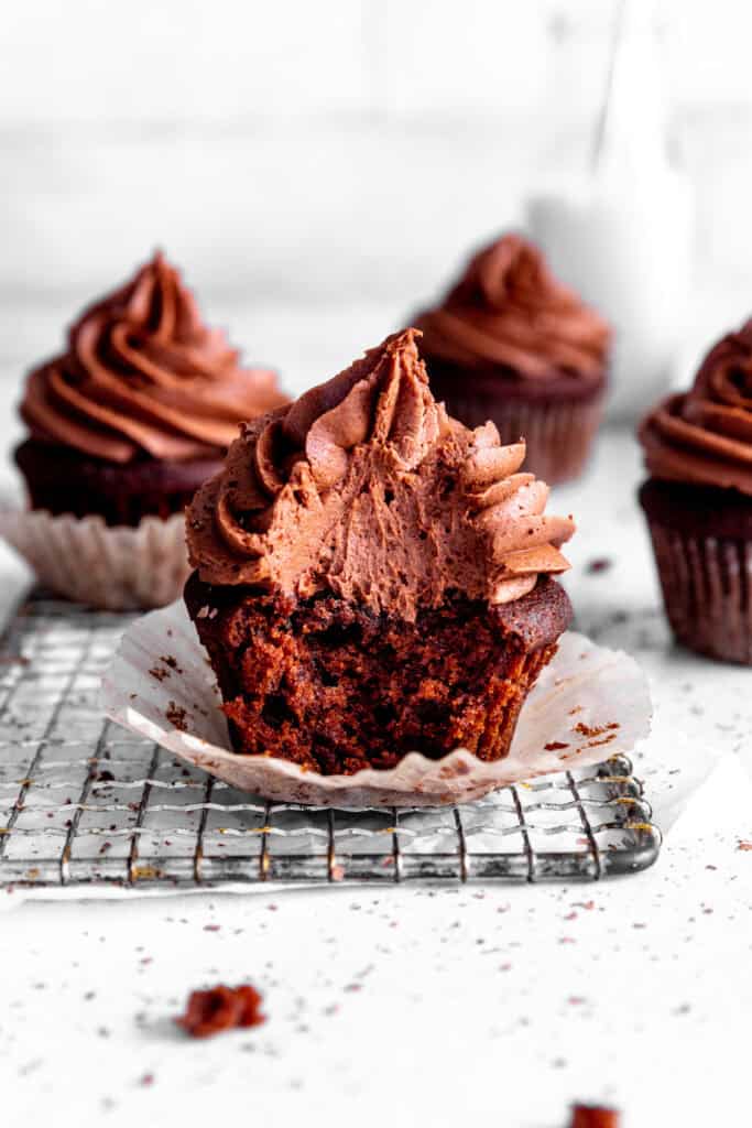 Chocolate cupcake with a bite taken out of it on a wire cooling rack.