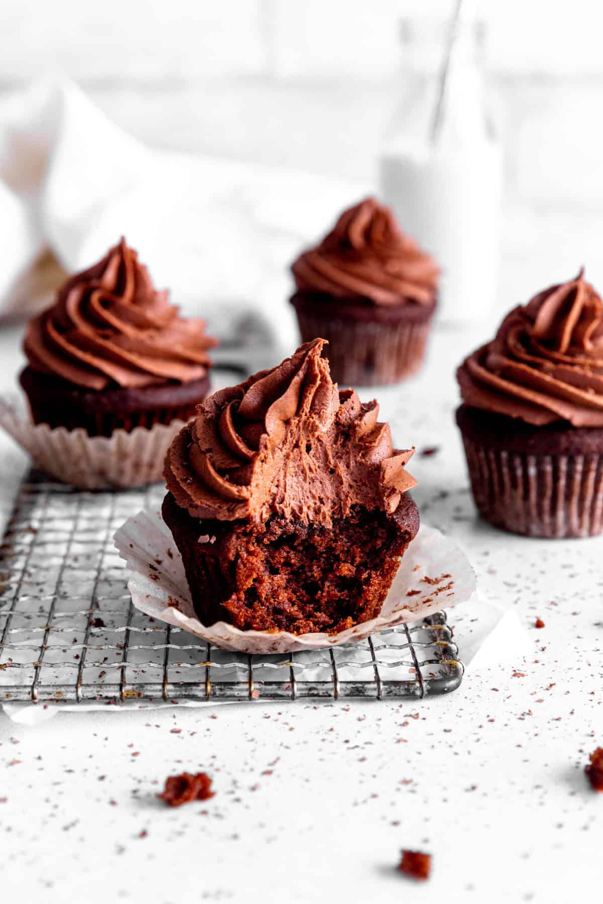 Chocolate cupcake with a bite taken out of it on a wire cooling rack.