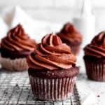 Chocolate cupcakes on a wire rack on a white countertop.