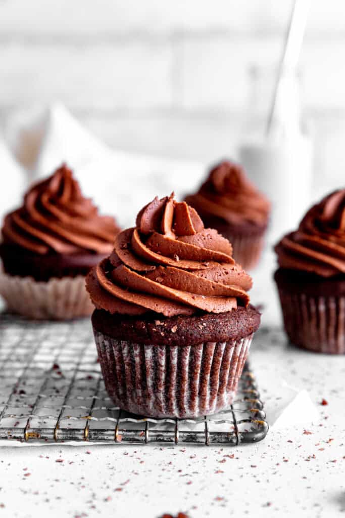 Chocolate cupcakes on a wire rack on a white countertop.