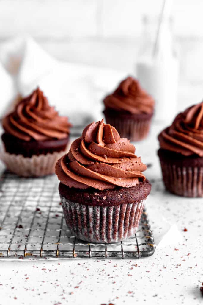 Chocolate cupcakes on a wire rack on a white countertop.