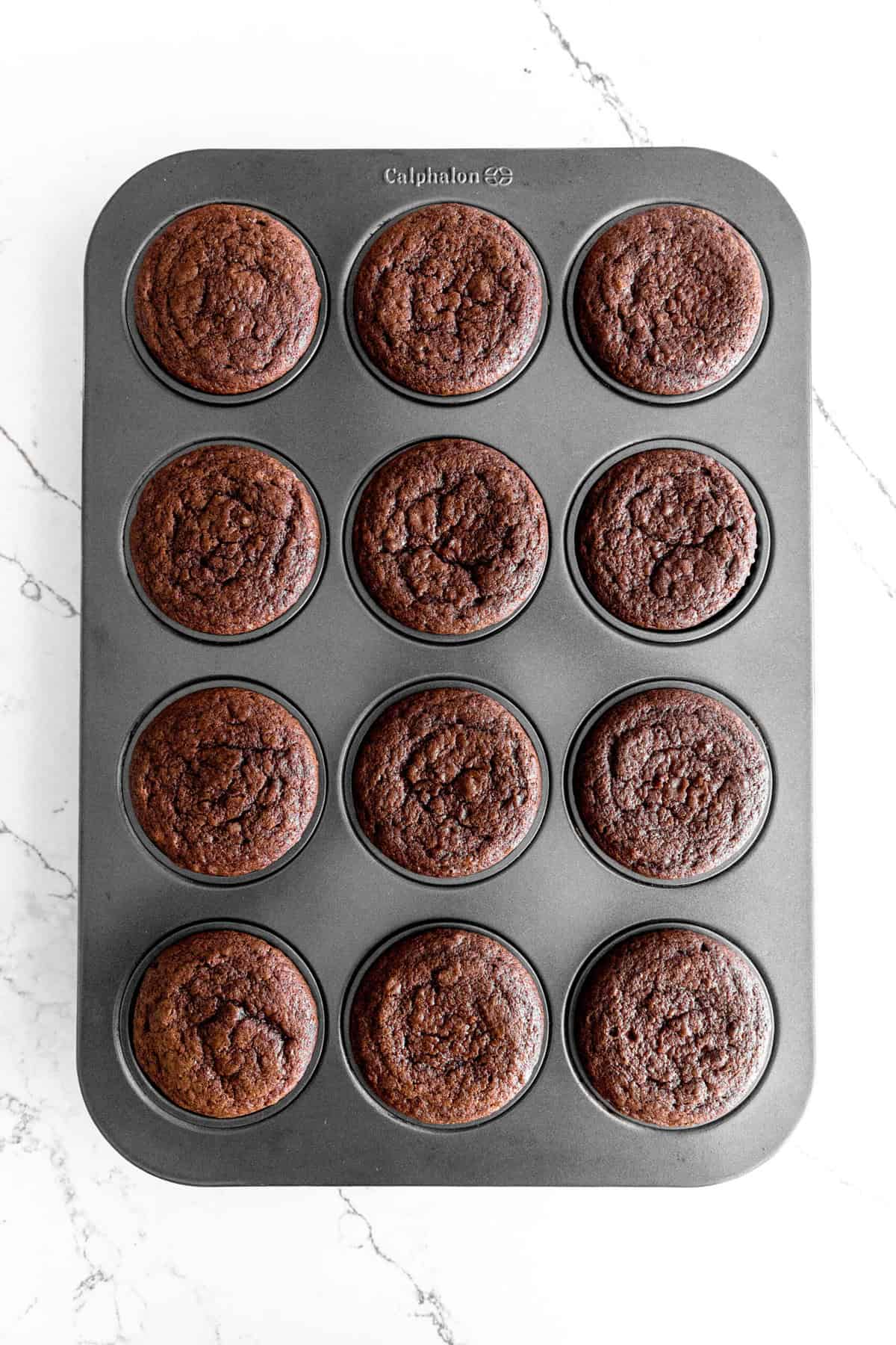 Baked chocolate cupcakes in a cupcake pan.