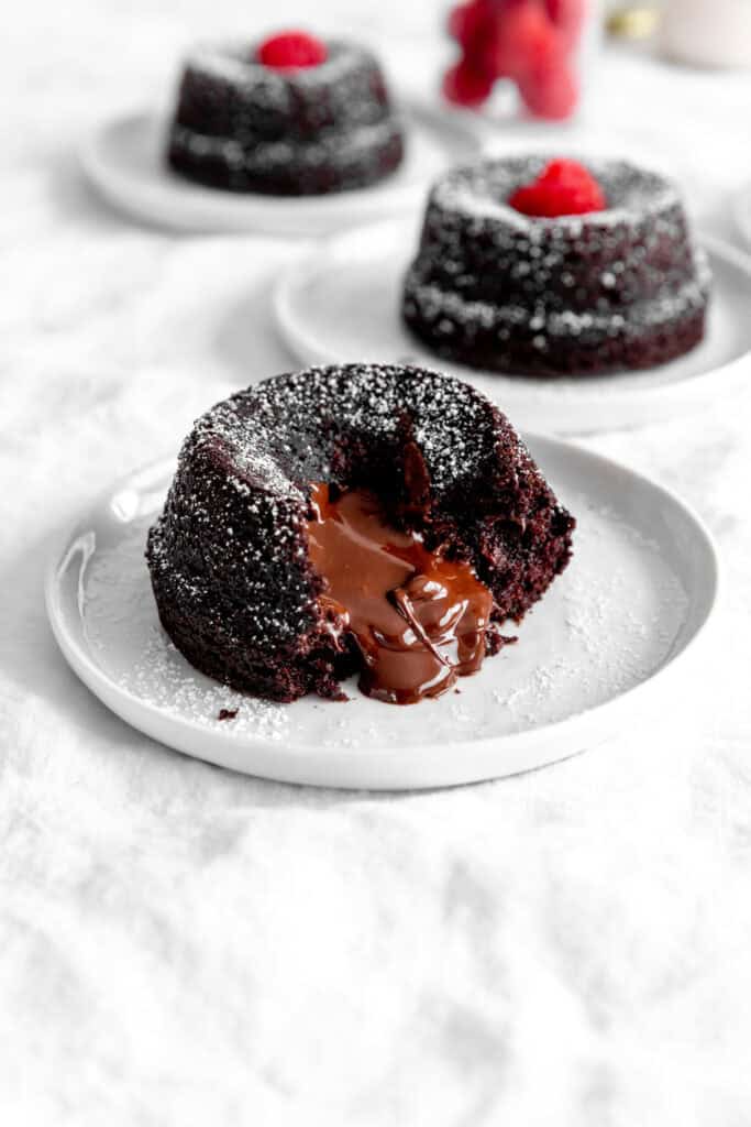 Chocolate lava cake on a white plate oozing chocolate sauce.