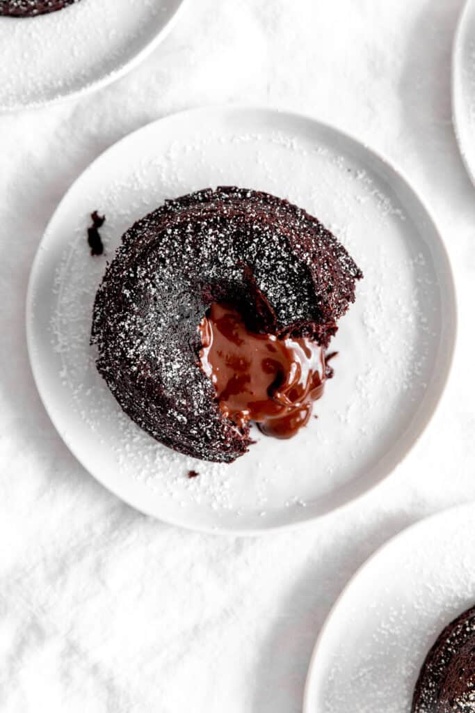 Chocolate lava cake on a white plate oozing chocolate sauce.