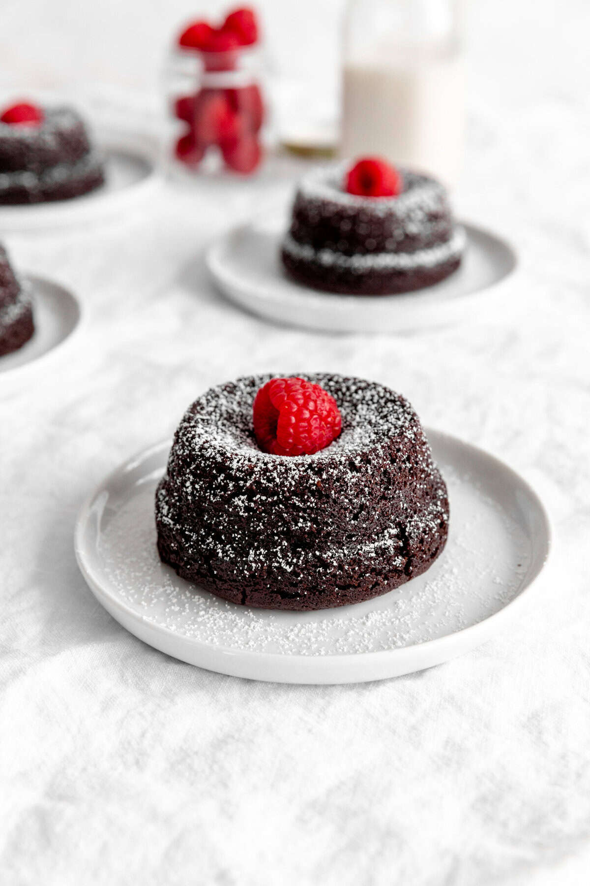 Chocolate lava cake topped with a raspberry on a white plate.