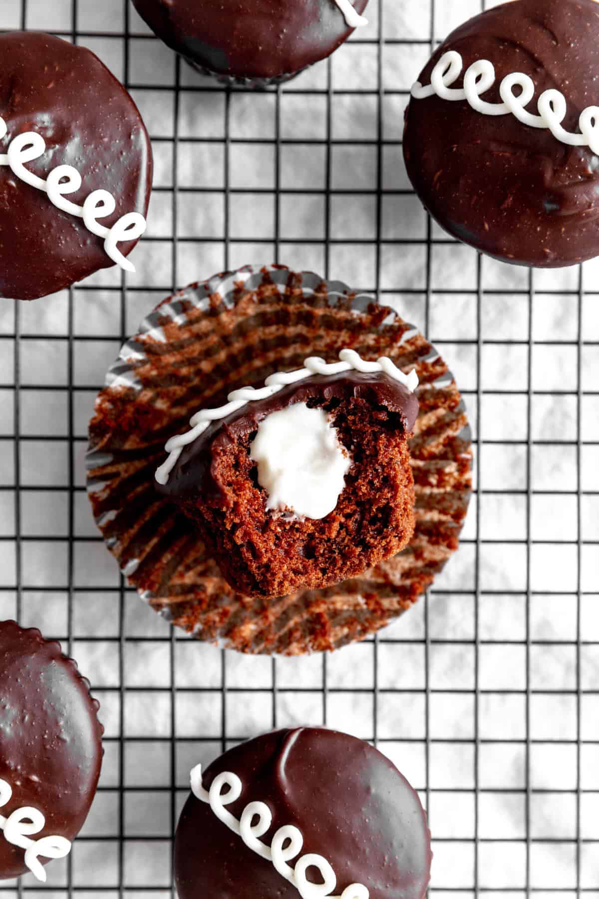 Hostess cupcake with a bite taken out of it laying on a wire cooling rack.