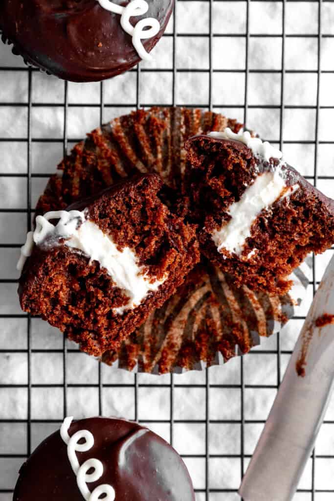 Hostess cupcake cut in half on a wire cooling rack and a knife.