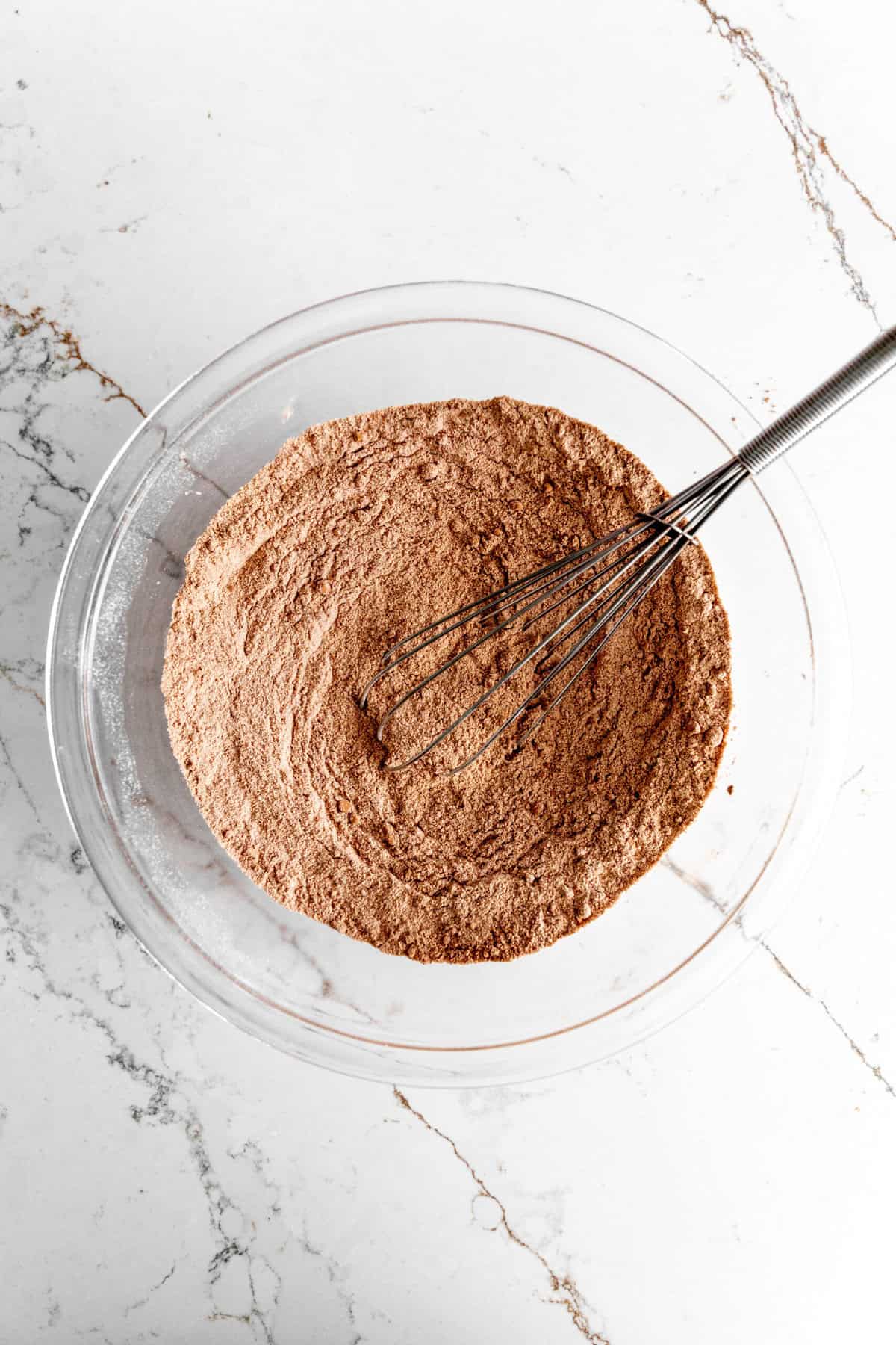 Glass bowl filled with dry ingredients for chocolate cupcakes.