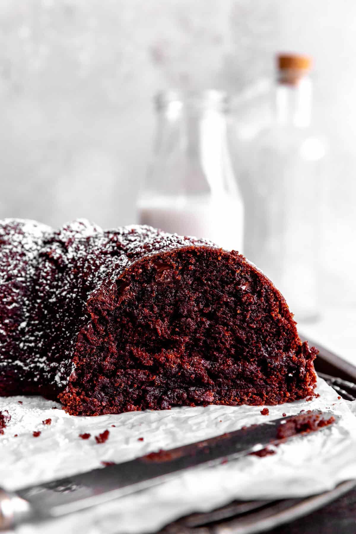 Sliced Kahlúa cake on a cooling rack with a knife in front of a jug of milk.