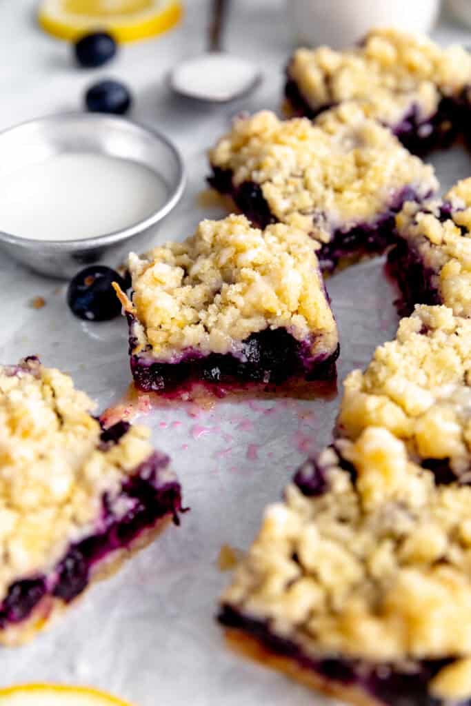 Lemon blueberry bars, a cup of glaze and a jug of milk.