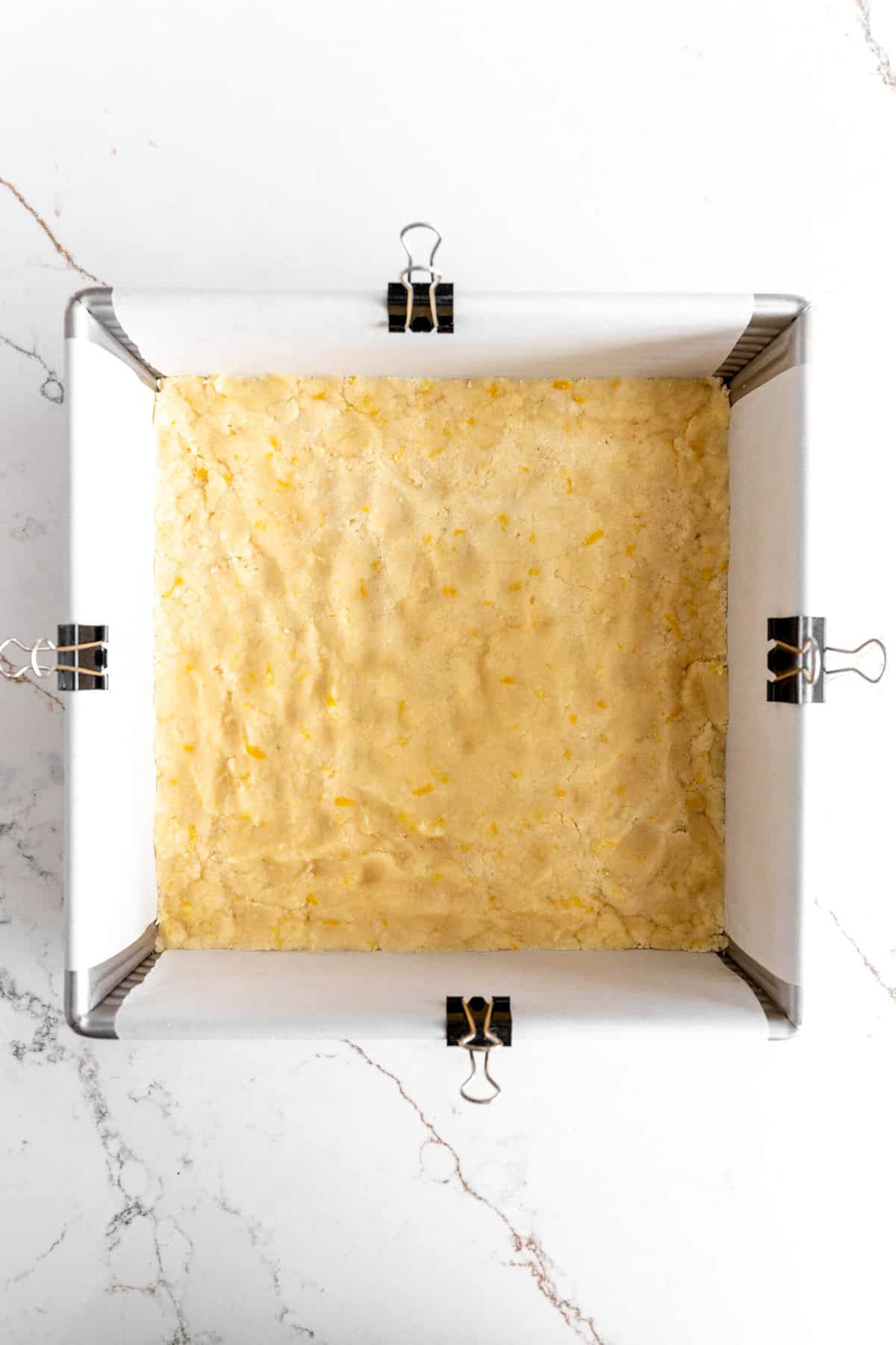 Unbaked lemon crust in a square baking pan.