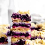 Stack of vegan lemon blueberry bars in front of a jug of milk.